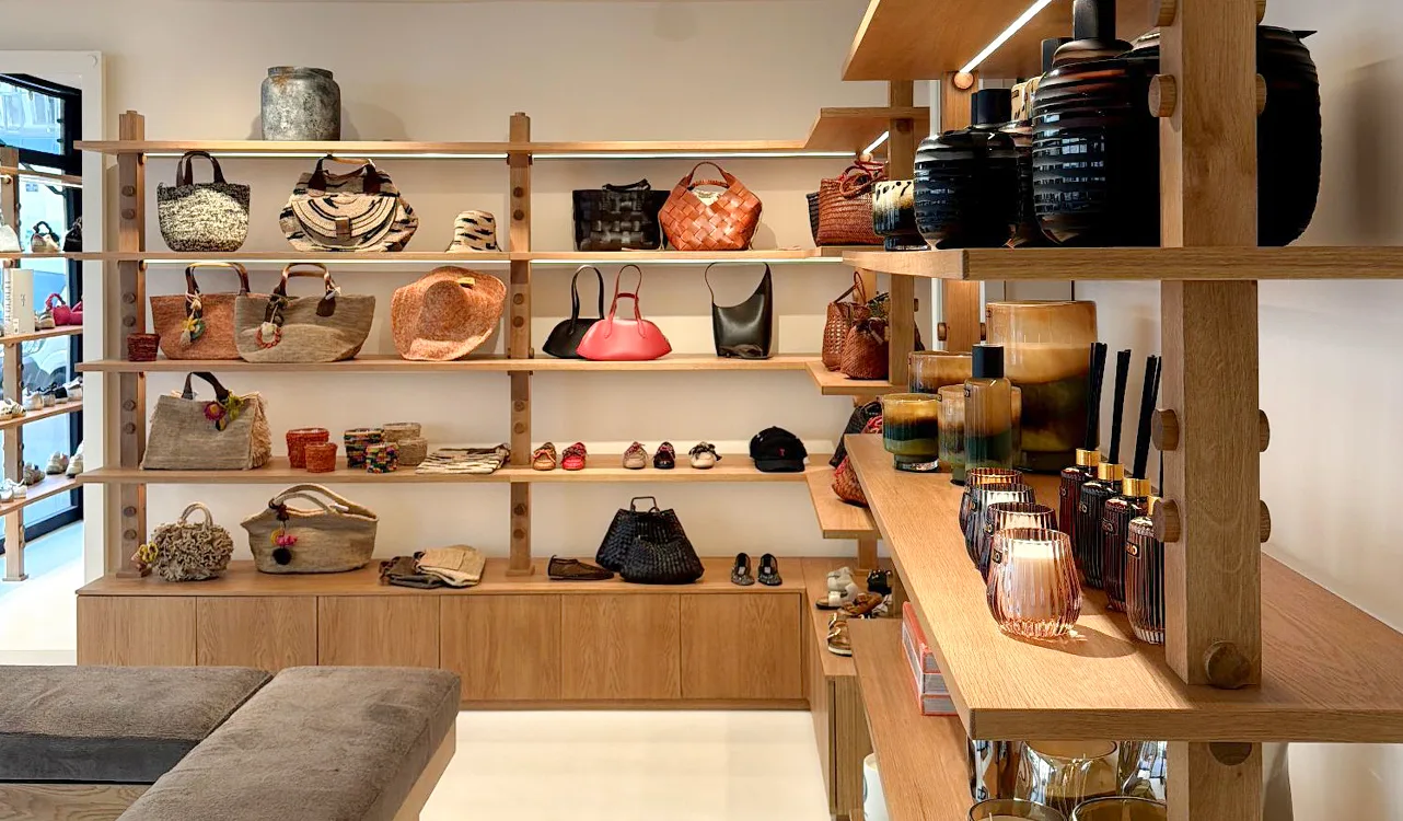Light wood shelves in the Lulli boutique in Annecy, with bags, baskets, shoes and vases